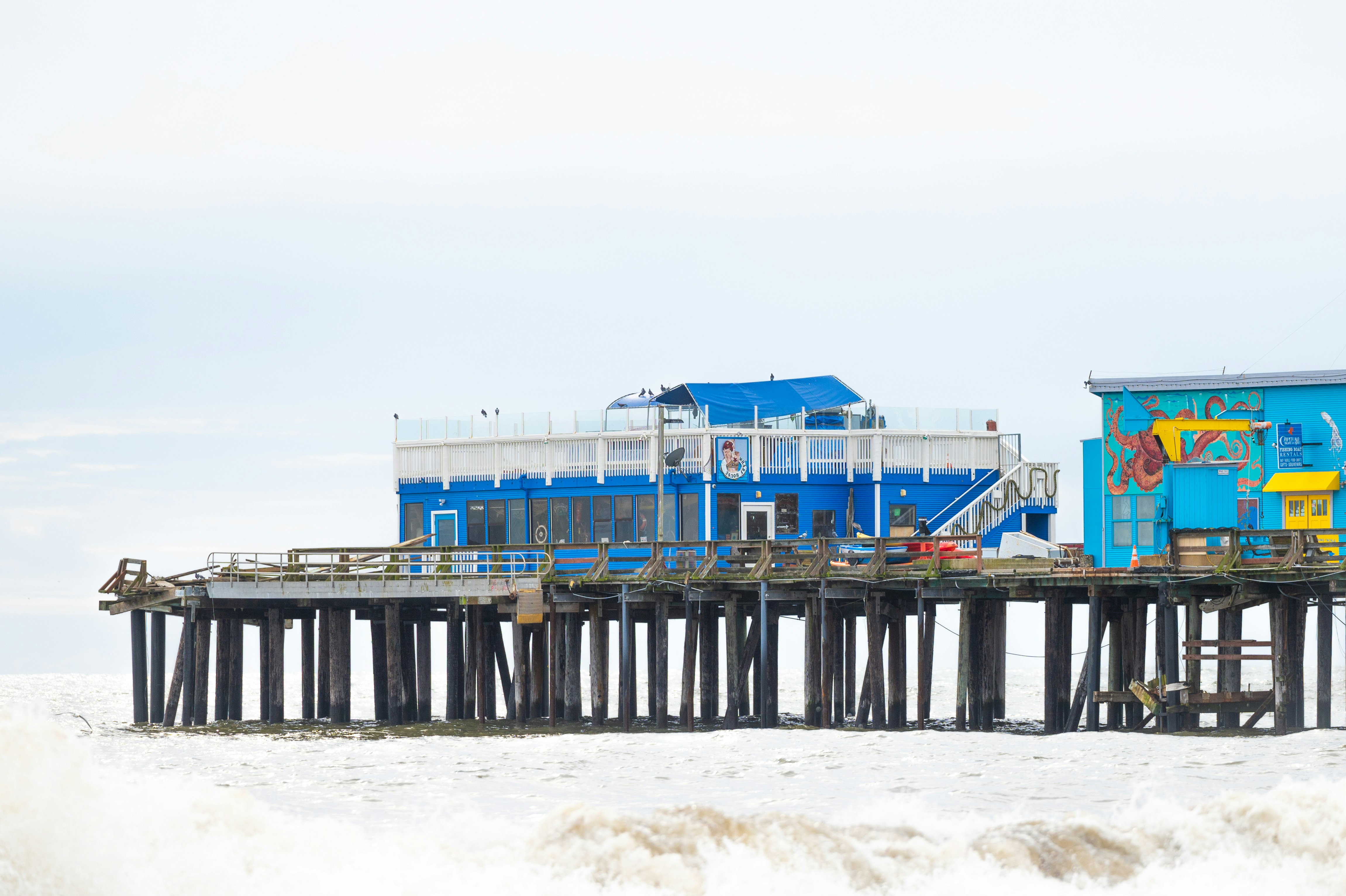 a blue and yellow building sitting on top of a pier