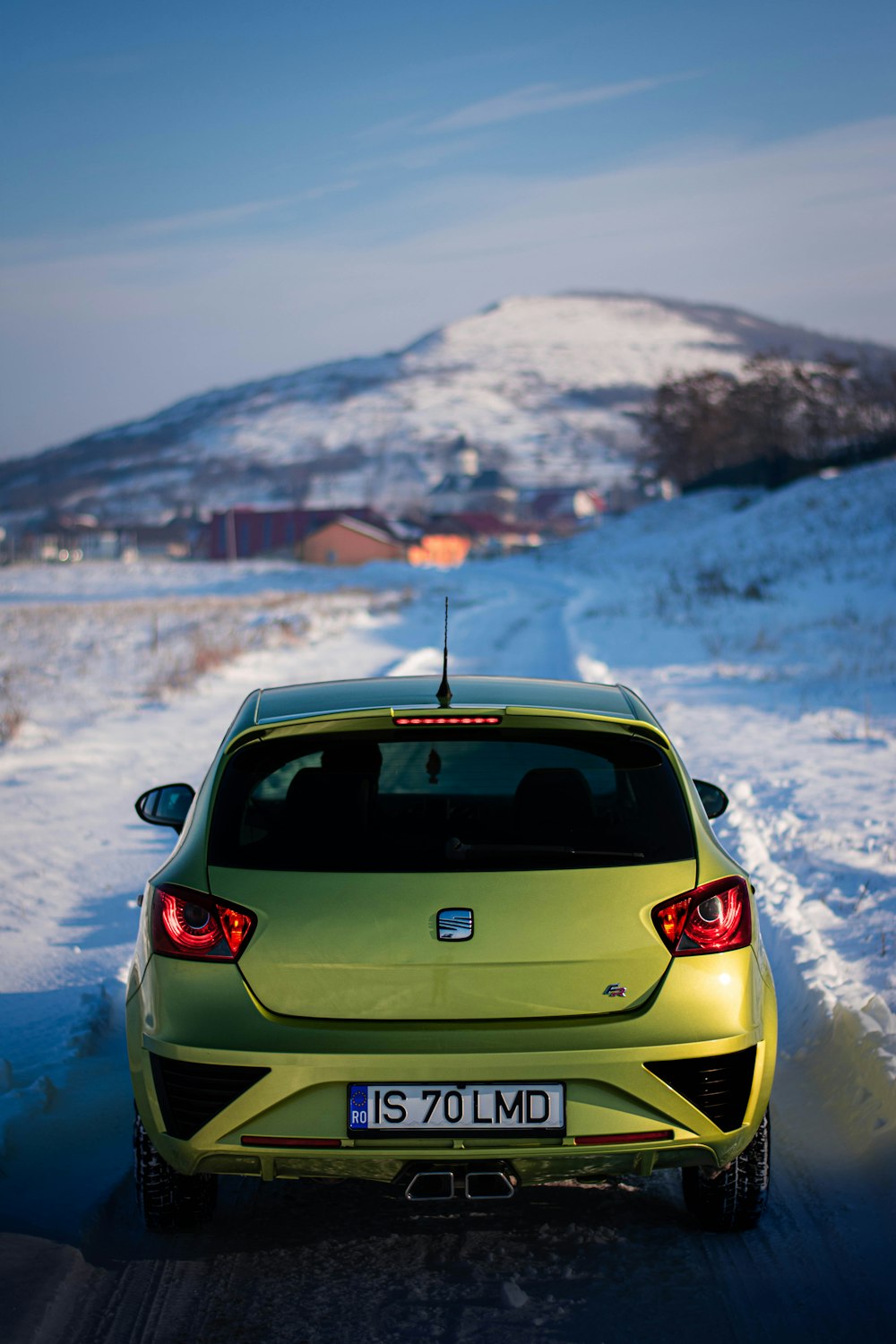 a yellow car driving down a snowy road