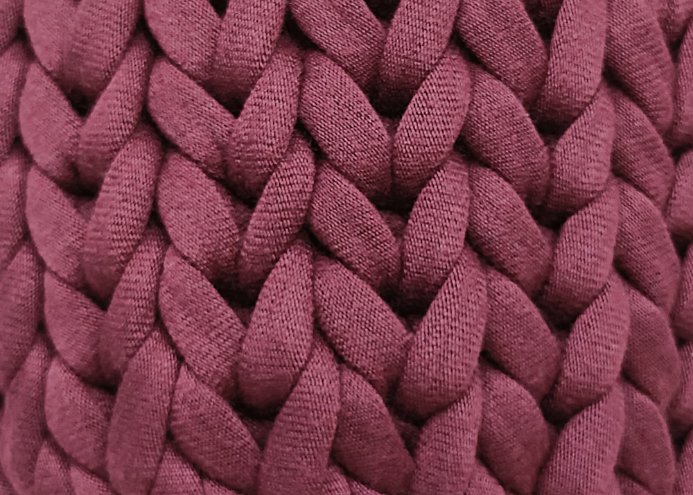 a close up of a purple pillow with braiding
