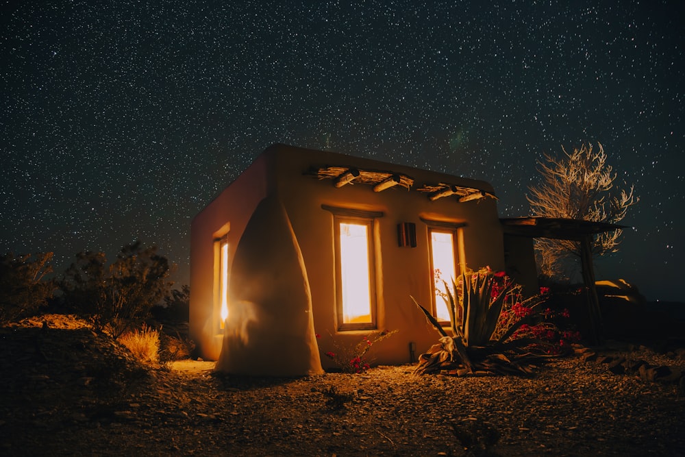 a small house sitting on top of a hill under a night sky