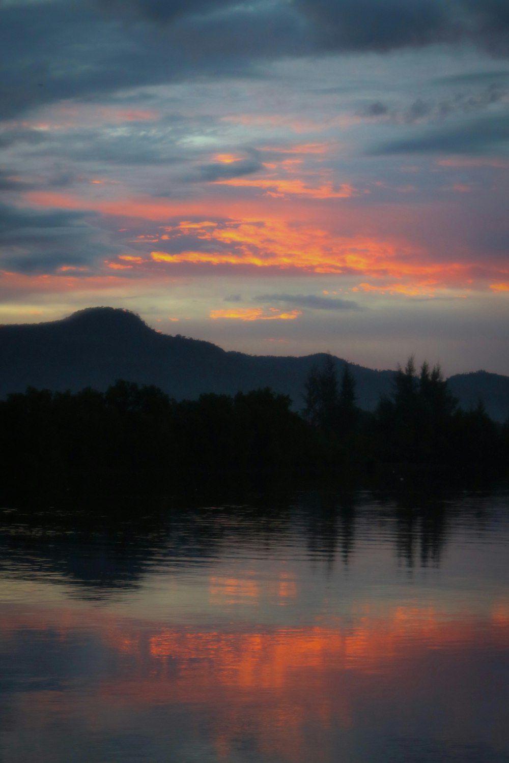 a sunset over a body of water with a mountain in the background