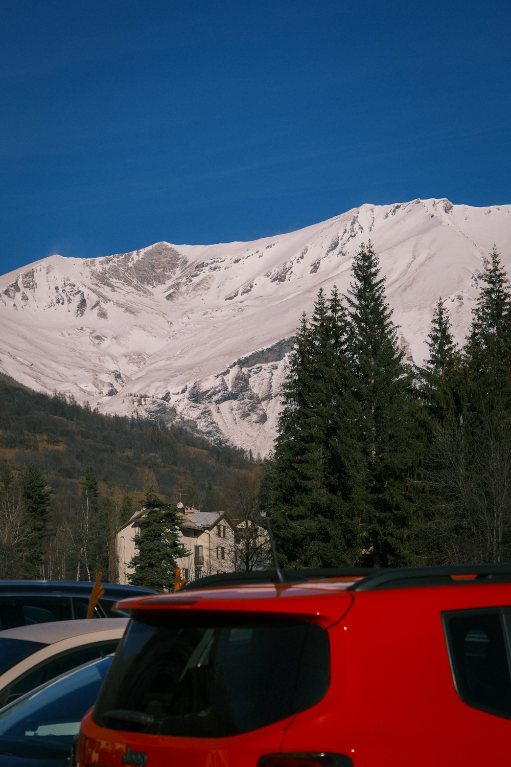 a red car parked in front of a snow covered mountain