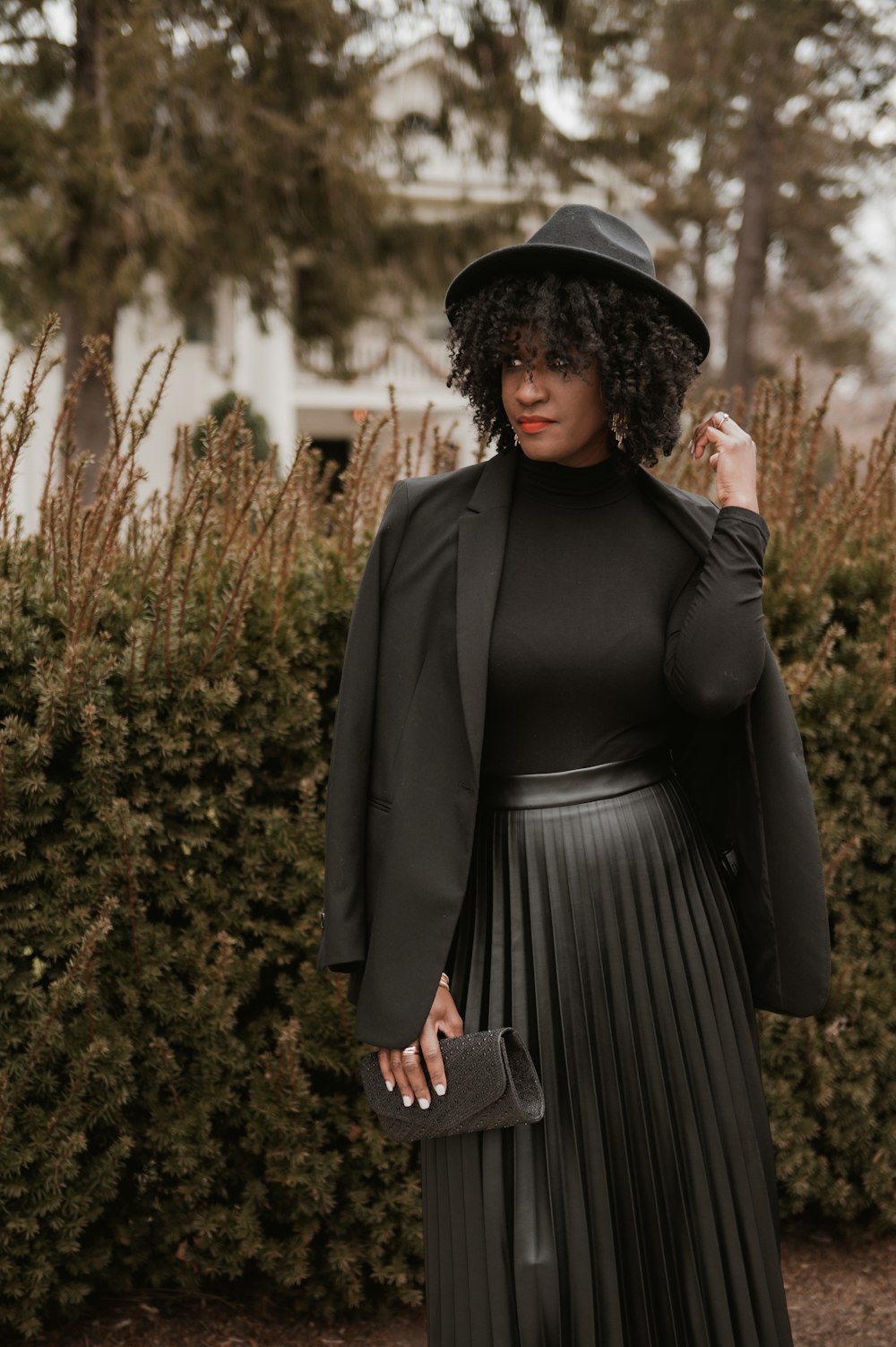 a woman wearing a black hat and a pleated skirt