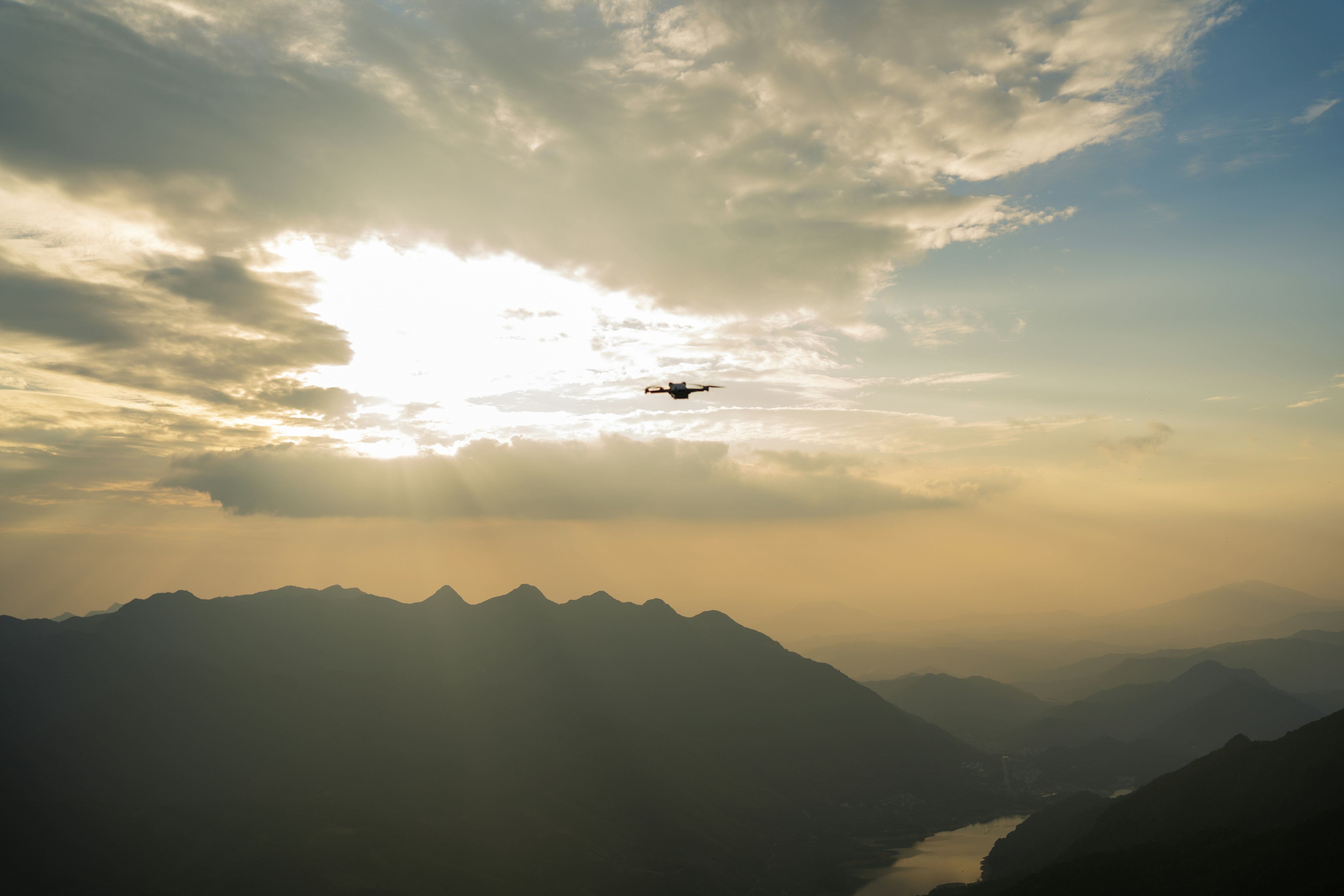 Drone flying over mountain landscape at golden hour, aerial perspective