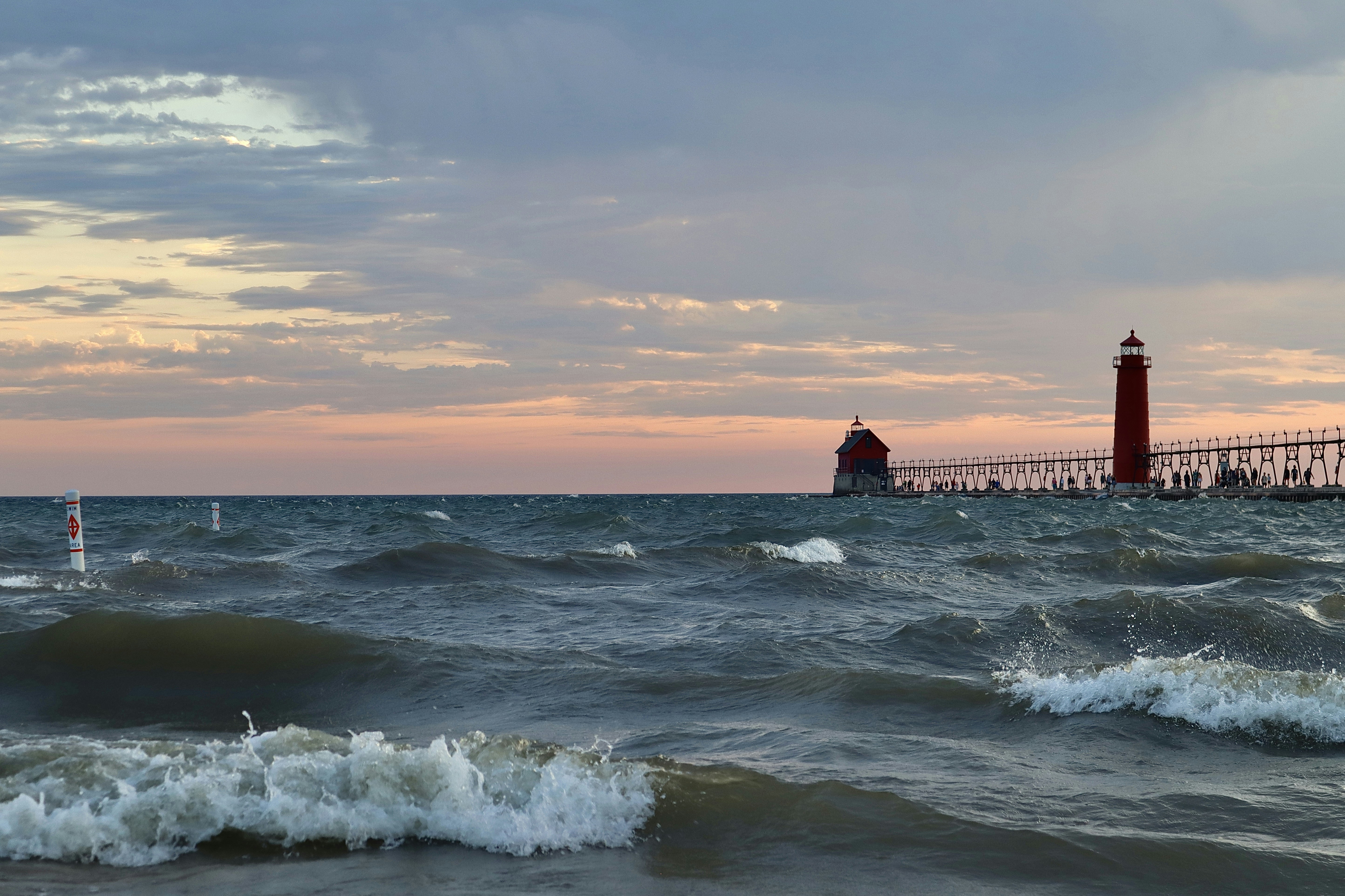 a red light house sitting on top of a pier next to the ocean