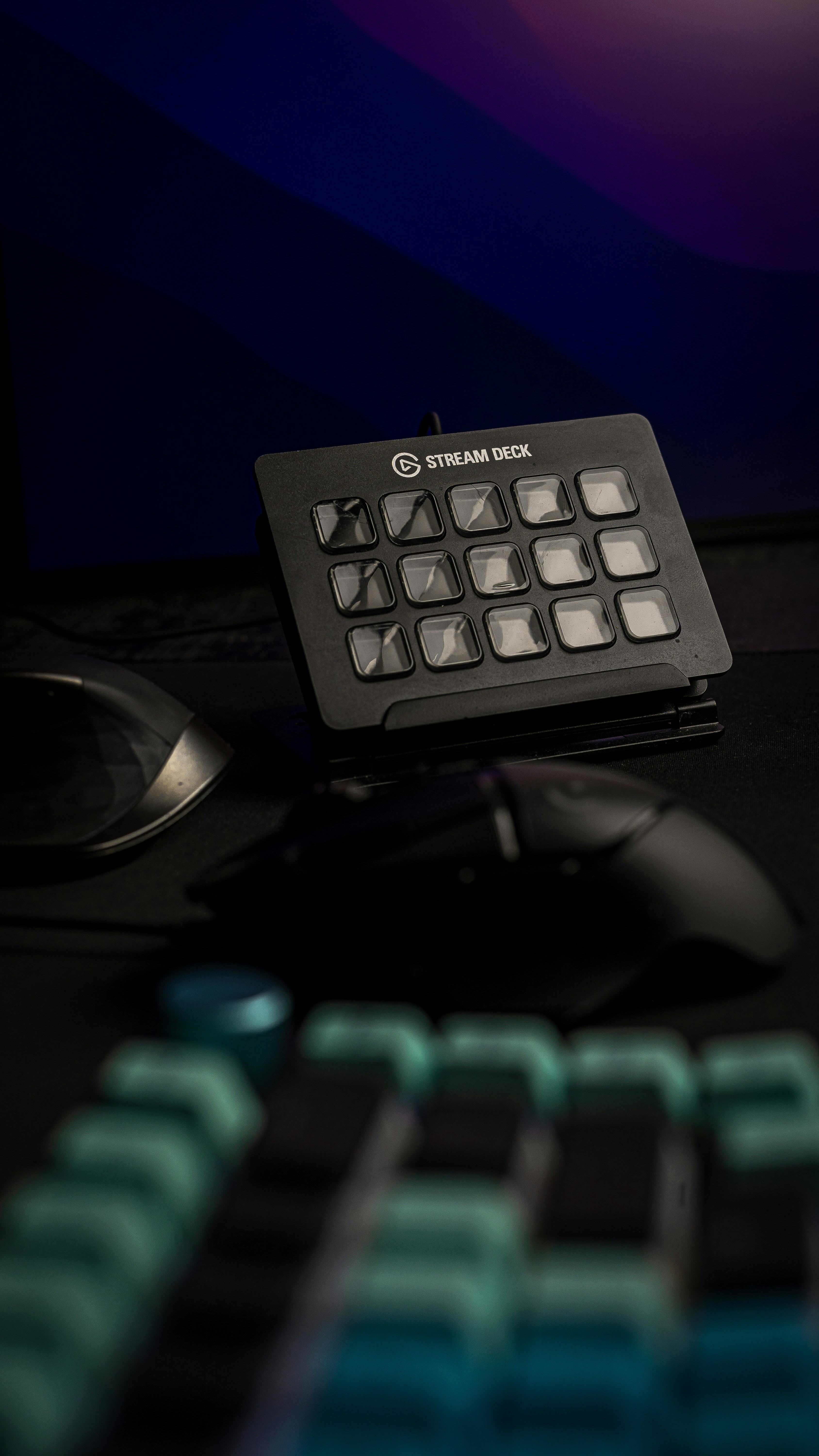 Black 15-key Elgato Stream Deck on its stand on a dark desk beside a computer mouse