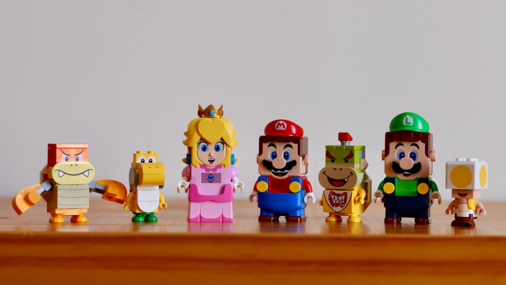 a group of nintendo figurines sitting on top of a wooden table