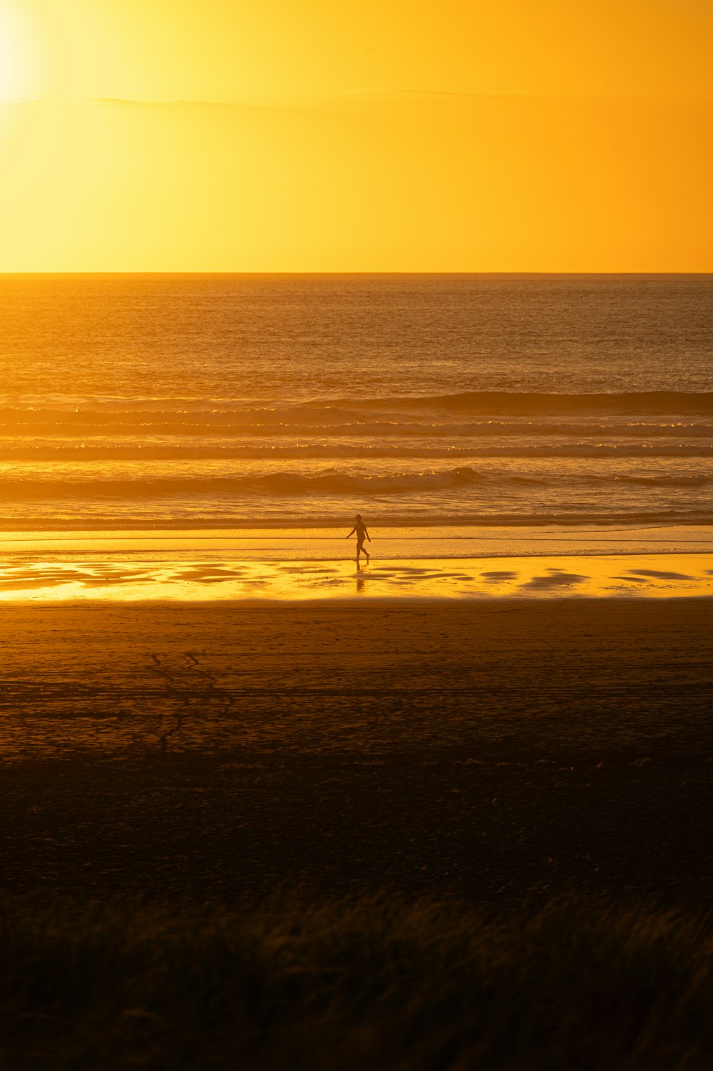 una persona che cammina sulla spiaggia al tramonto