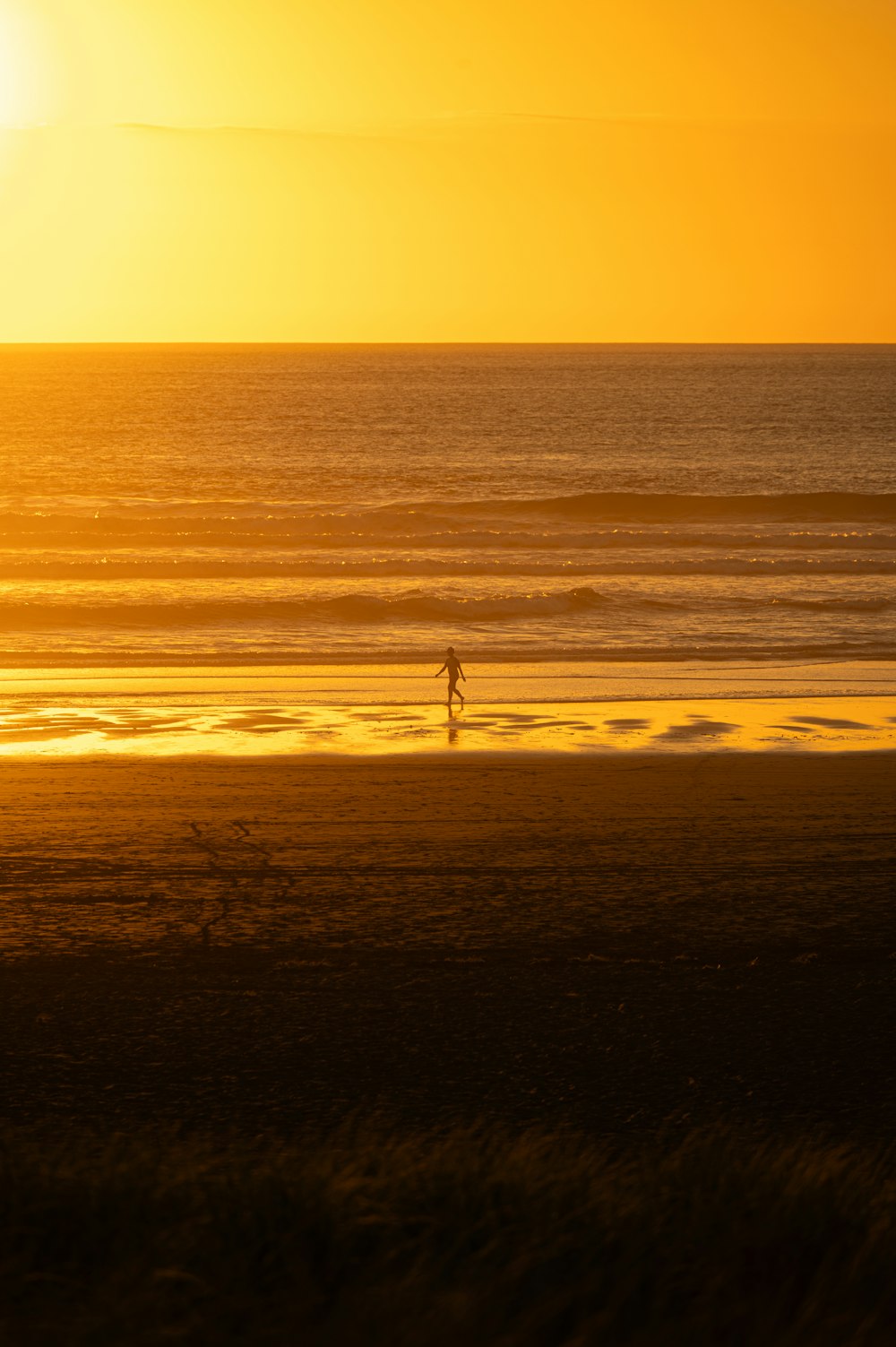 a person walking on the beach at sunset