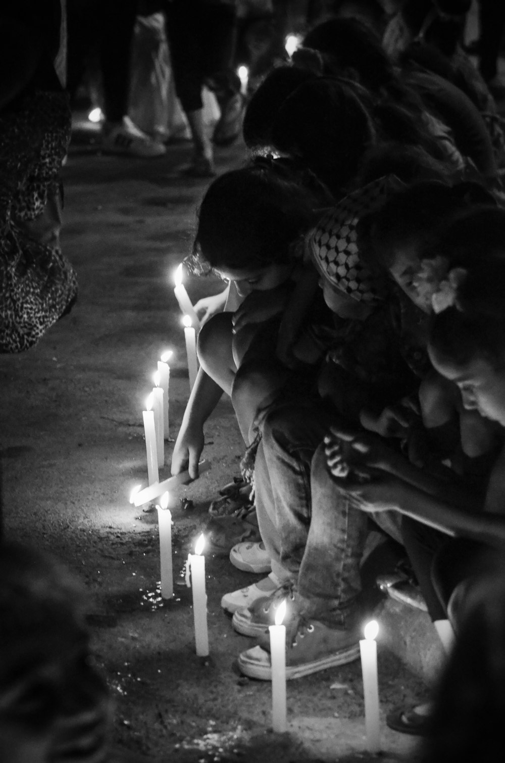 a group of people sitting on the ground with candles in front of them