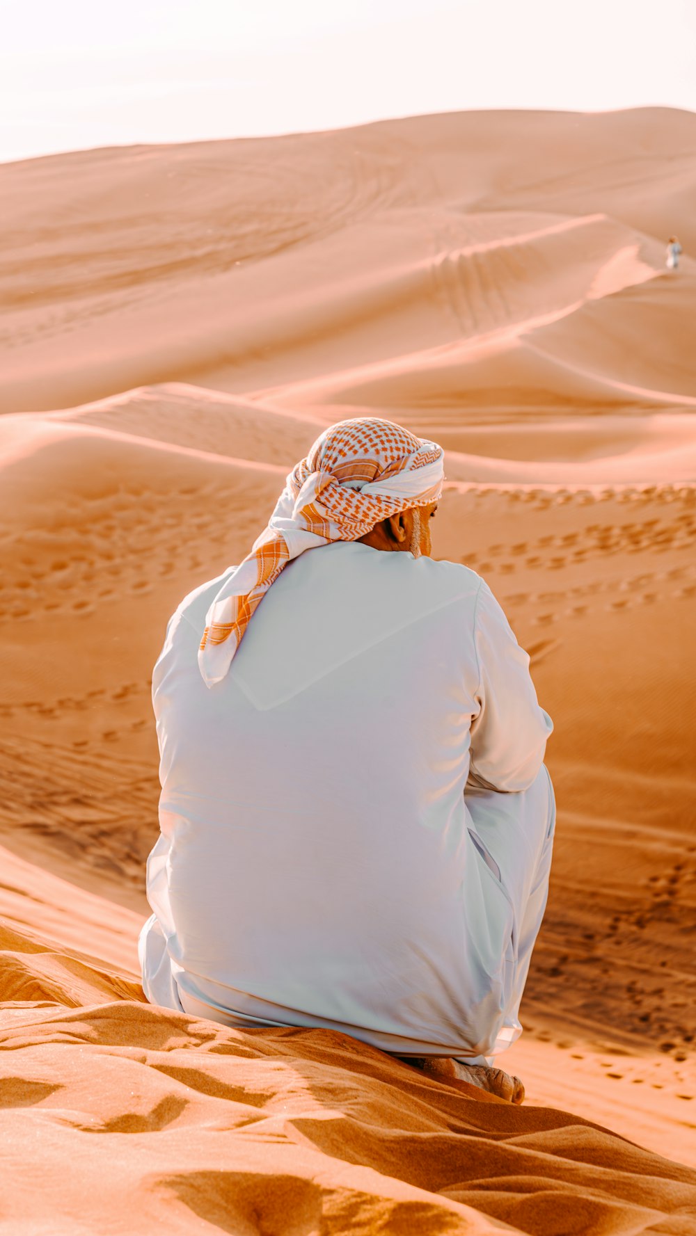 a man sitting on top of a sandy dune