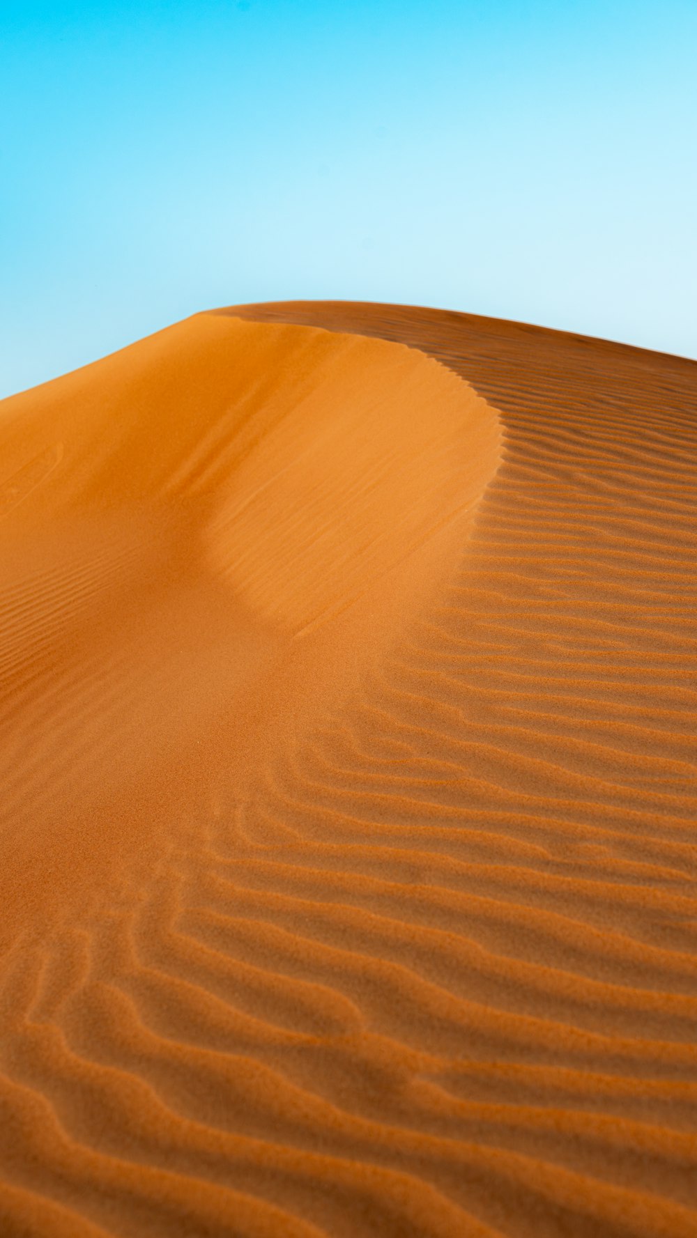 a large sand dune with a blue sky in the background