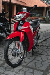 a red motorcycle is parked on a cobblestone street