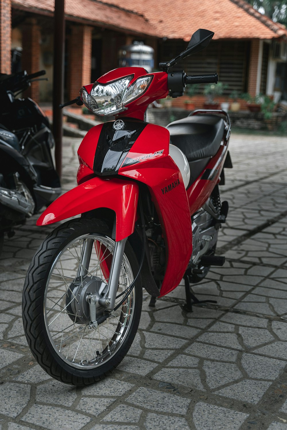 Ein rotes Motorrad parkt auf einer Kopfsteinpflasterstraße