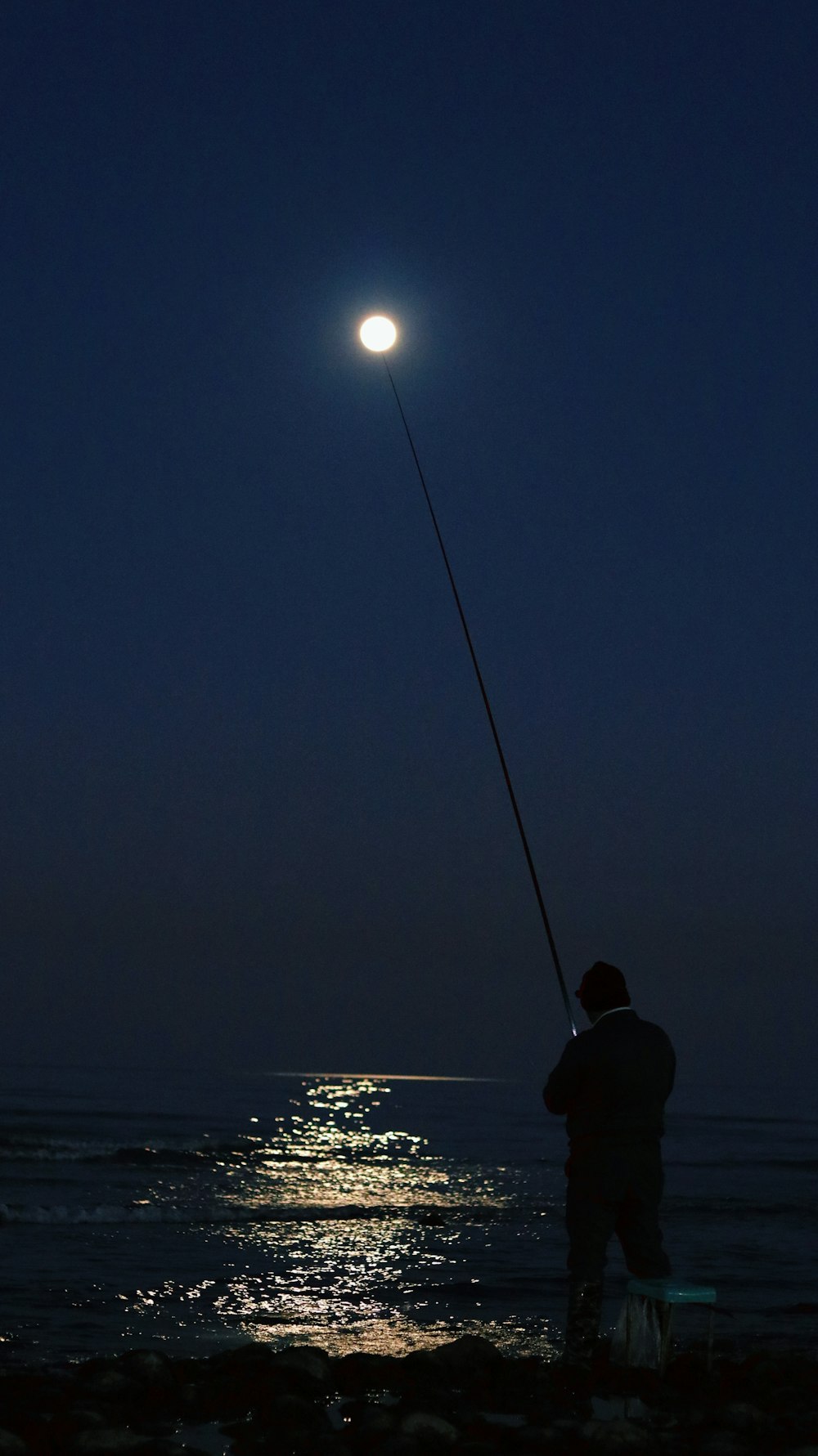 un uomo in piedi su una spiaggia con in mano una canna da pesca