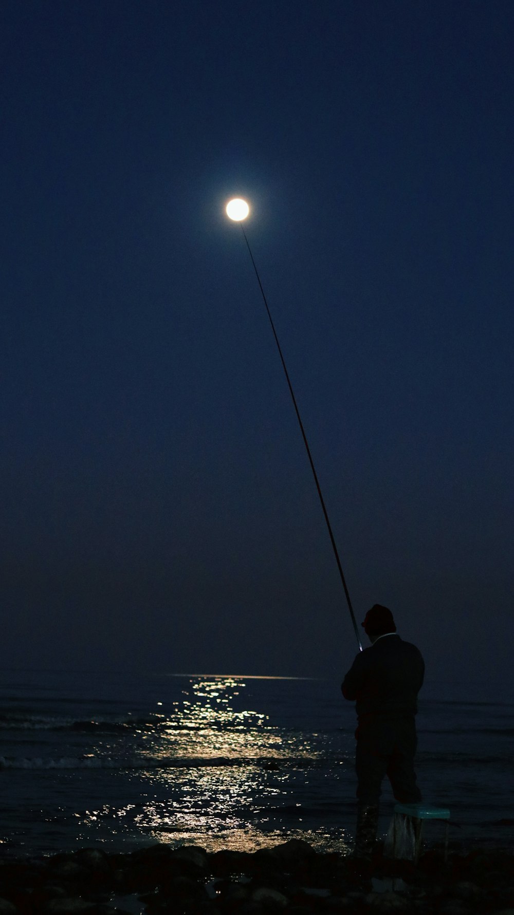 a man standing on a beach holding a fishing pole