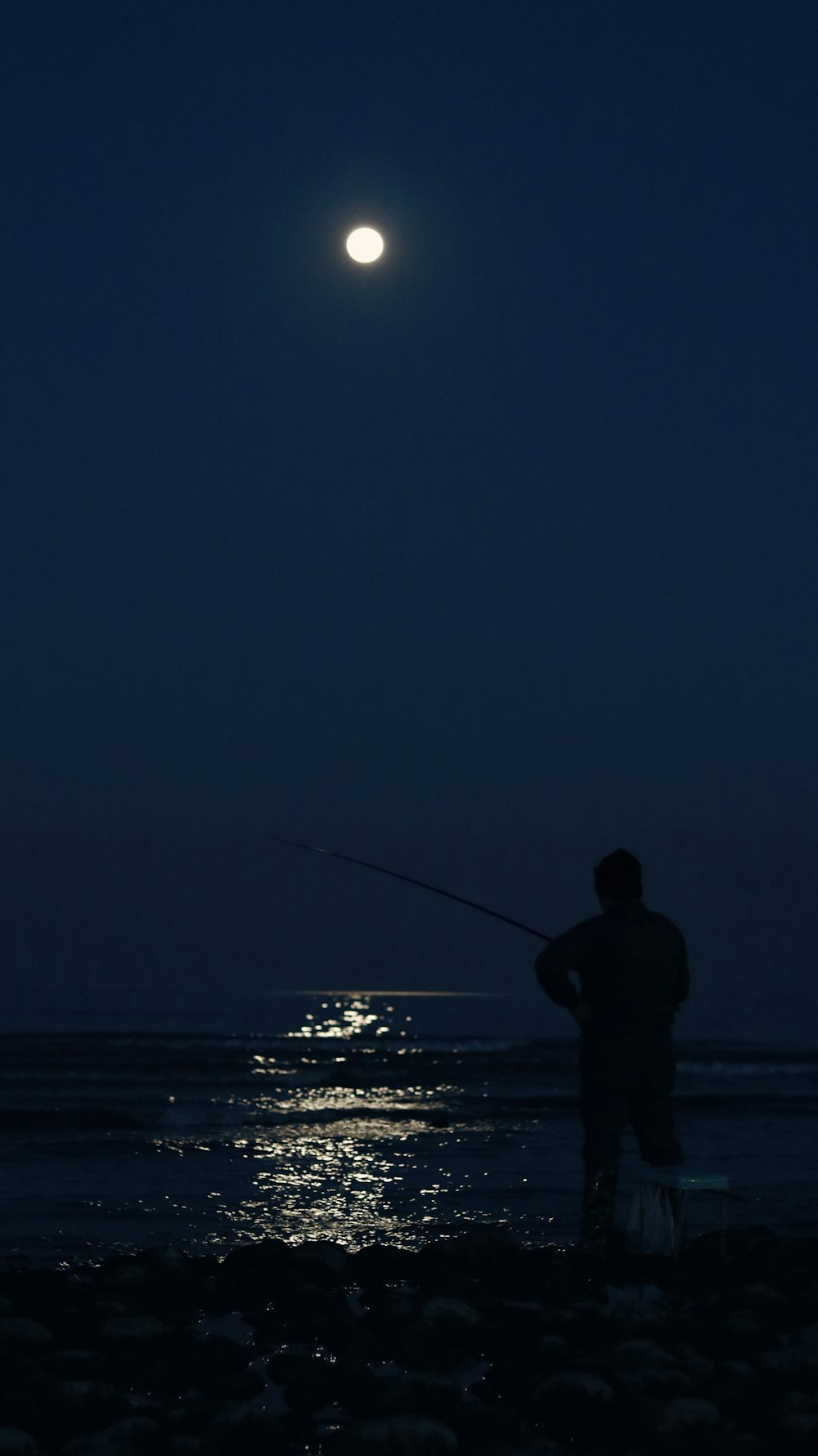 um homem pescando na praia à noite