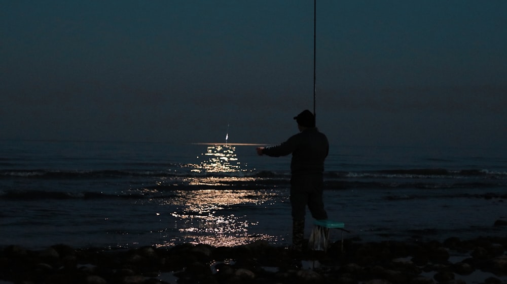 a man fishing on the ocean at night