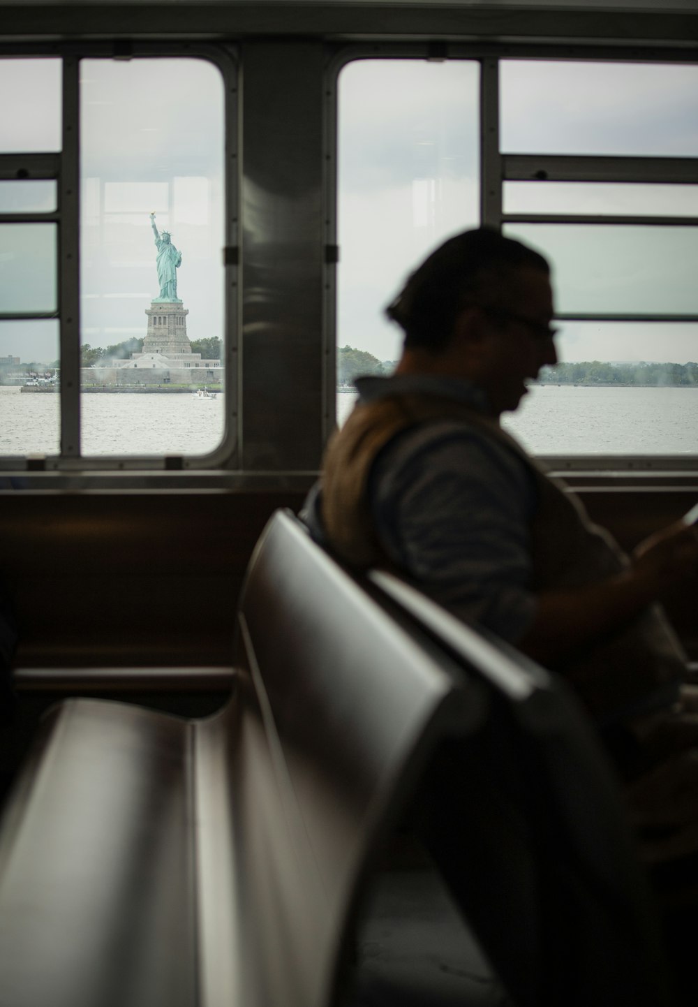 a man sitting on a train next to a statue of liberty