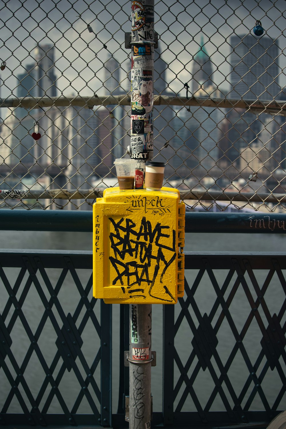 a yellow box with graffiti on it sitting next to a fence