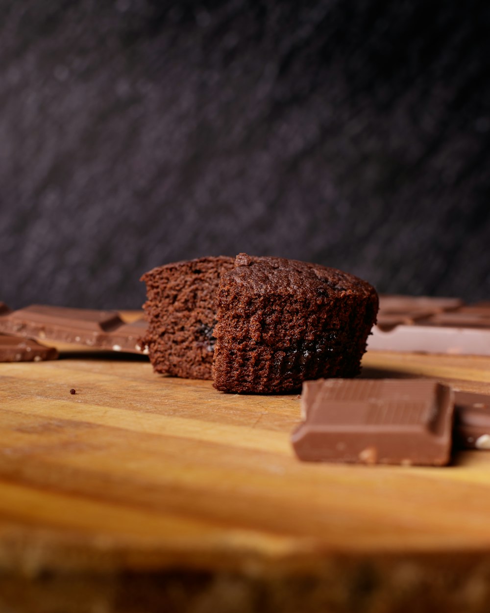 a chocolate muffin sitting on top of a wooden cutting board