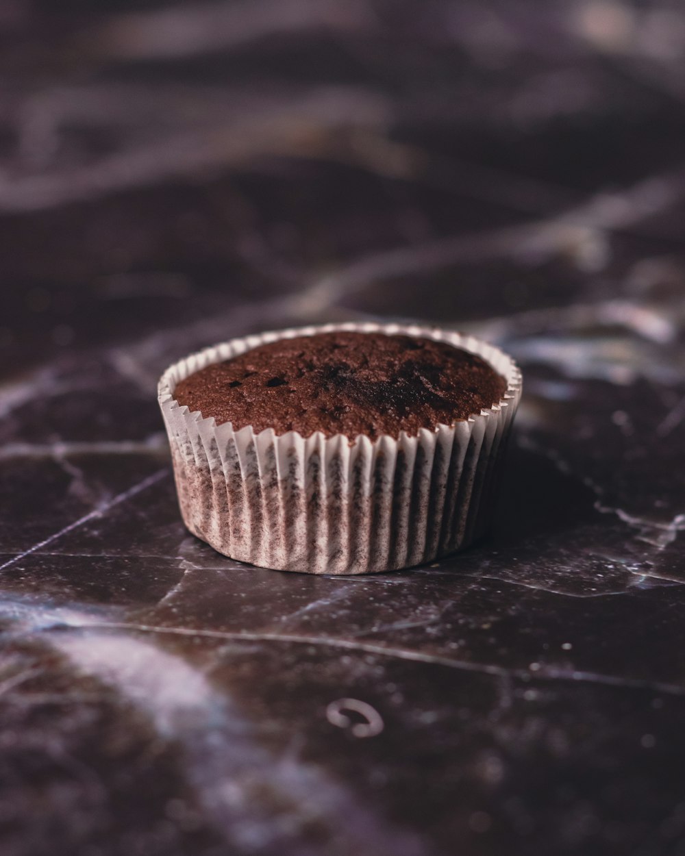 a chocolate cupcake sitting on a marble surface
