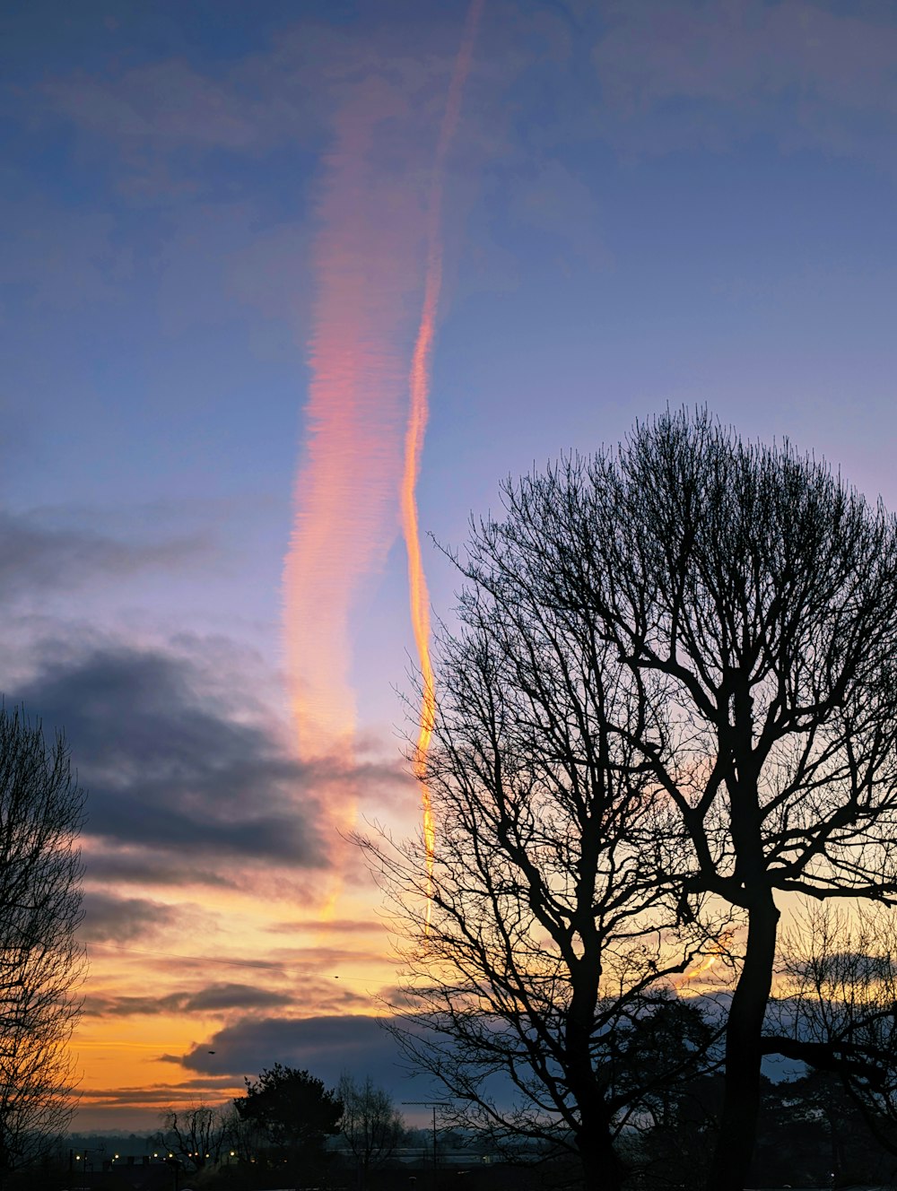 a contrail is seen in the sky above trees