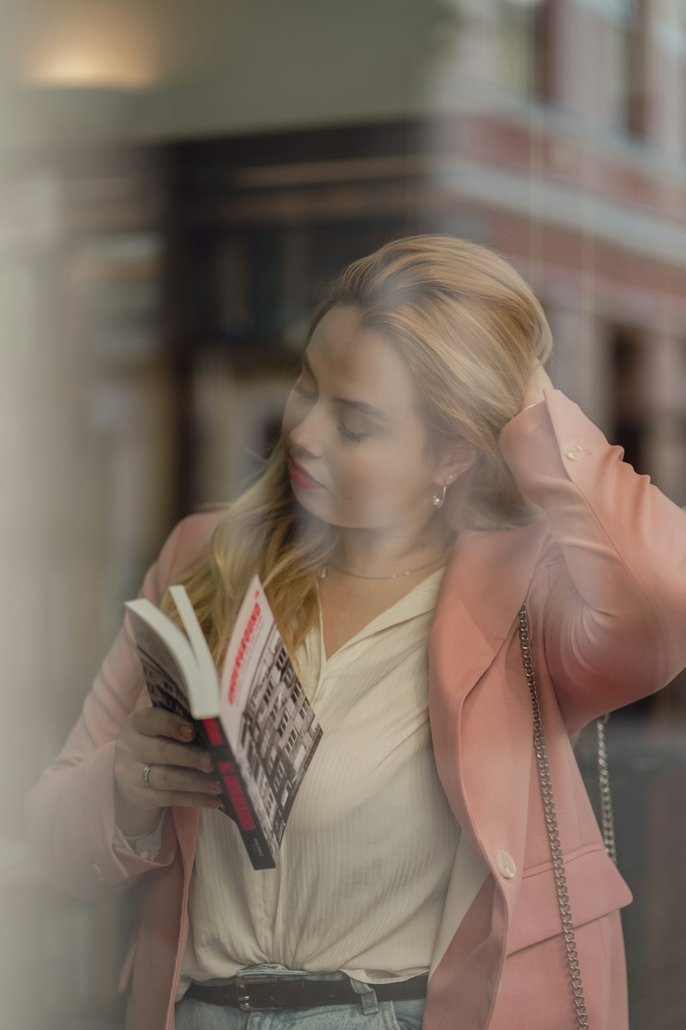 a woman in a pink jacket is reading a book