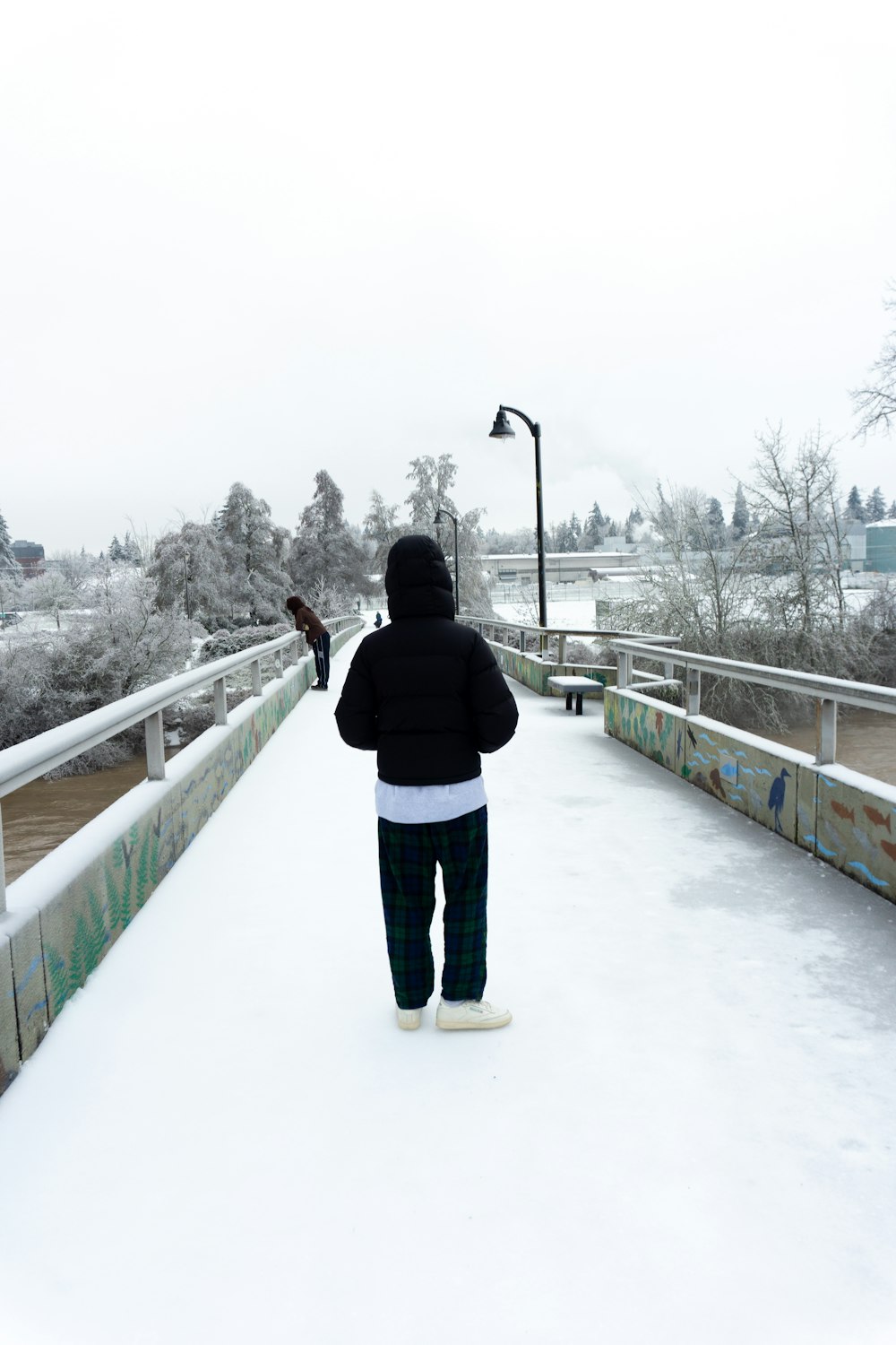 a person walking across a snow covered bridge
