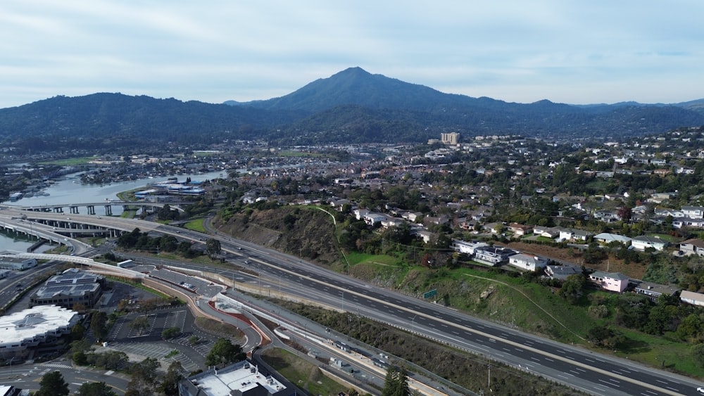 an aerial view of a city with a bridge and mountains in the background