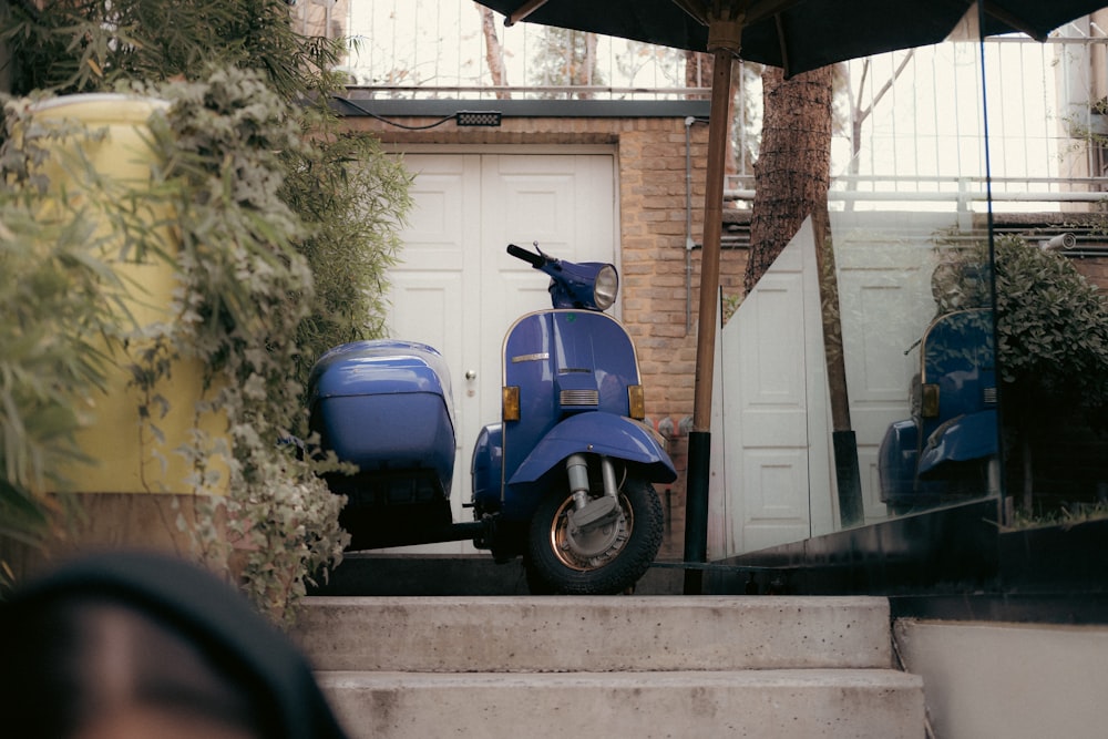 ein blauer Roller, der vor einem Haus geparkt ist