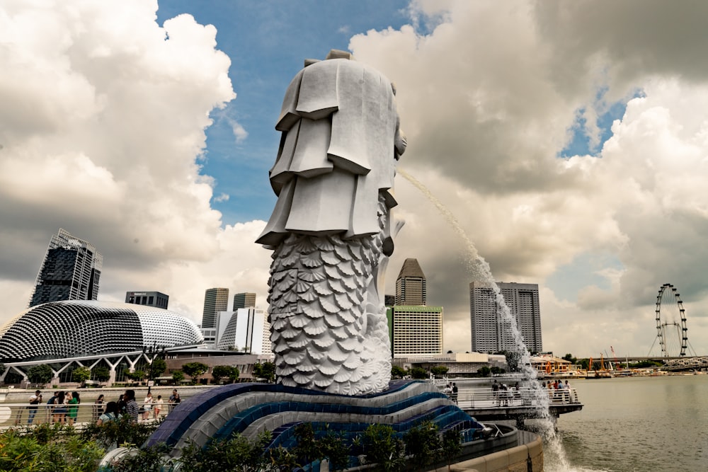 a statue of a man with a fish tail in front of a body of water