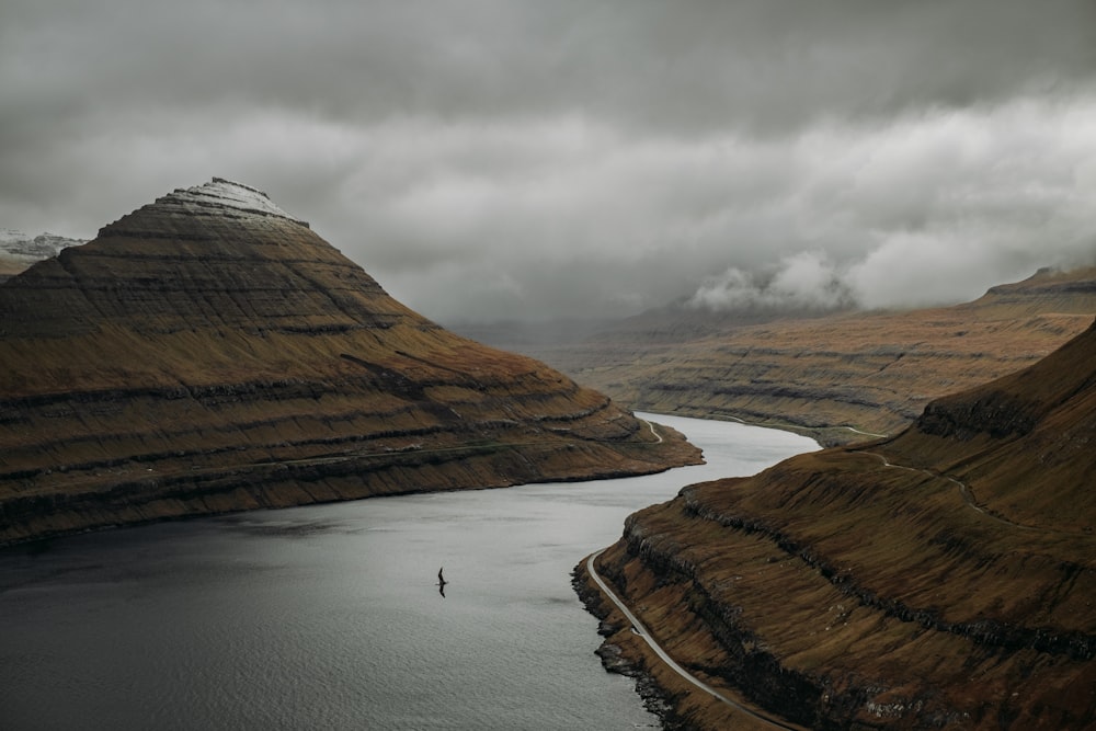 a body of water surrounded by mountains under a cloudy sky