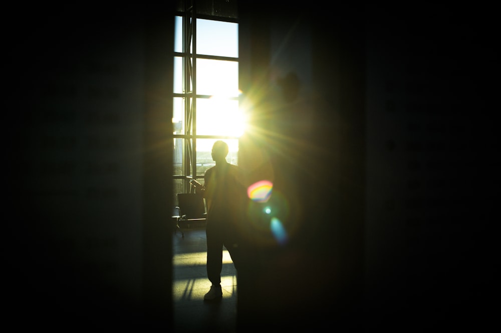 a person standing in front of a window with the sun shining through