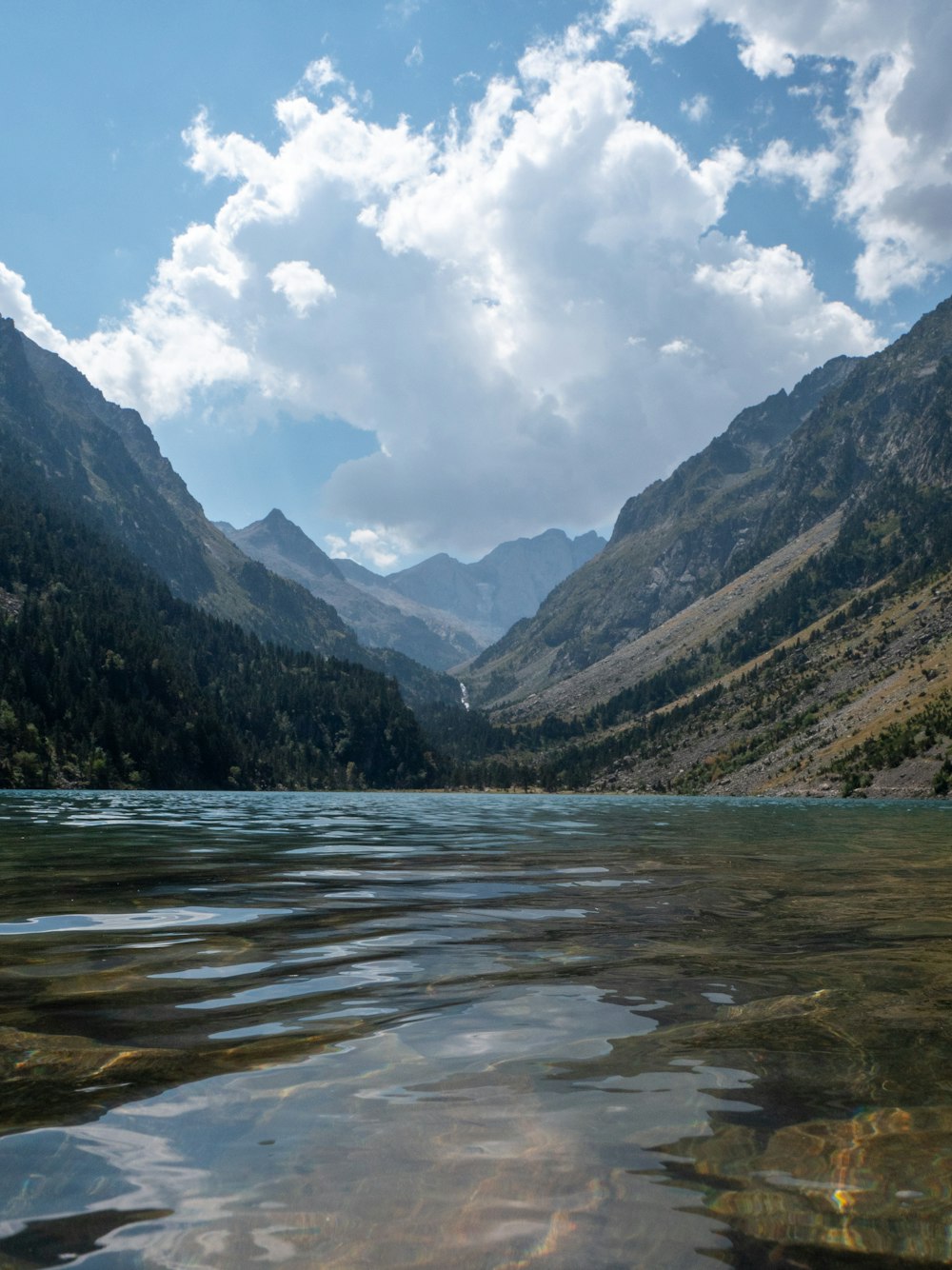 Un plan d’eau entouré de montagnes sous un ciel nuageux