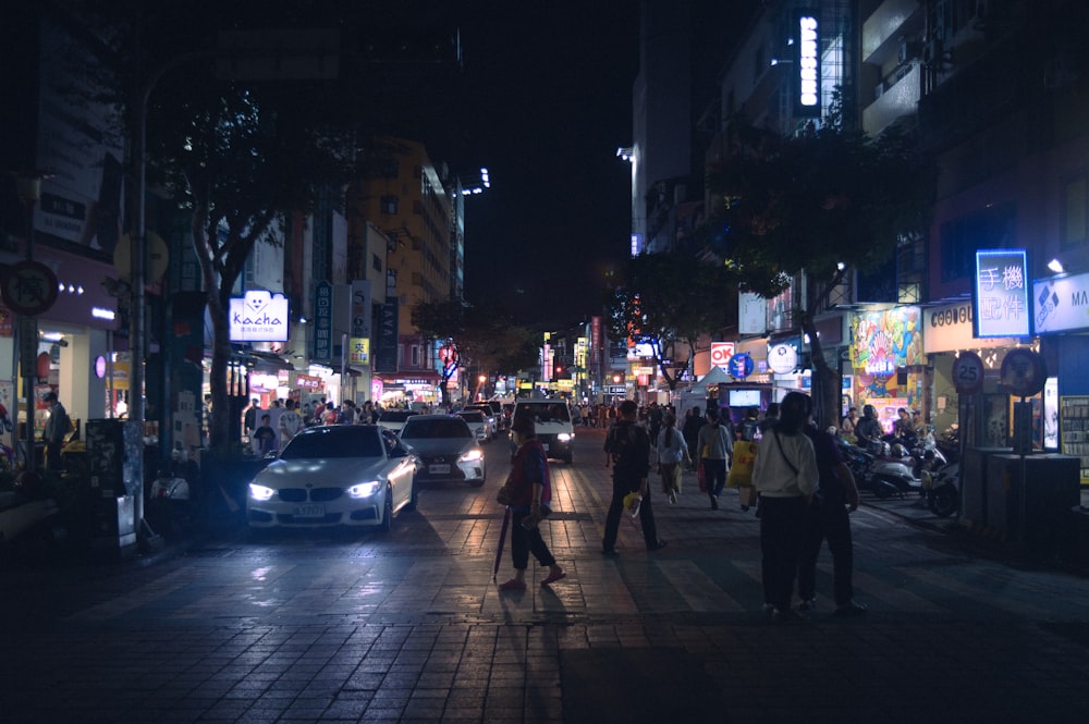 a city street at night filled with people and cars