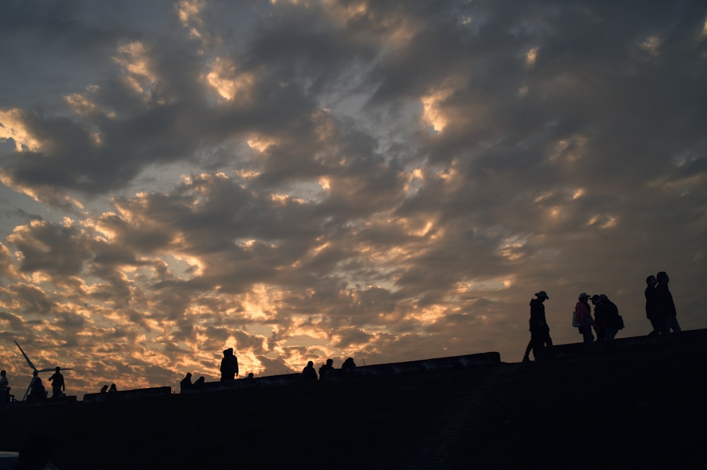 a group of people standing on top of a roof under a cloudy sky