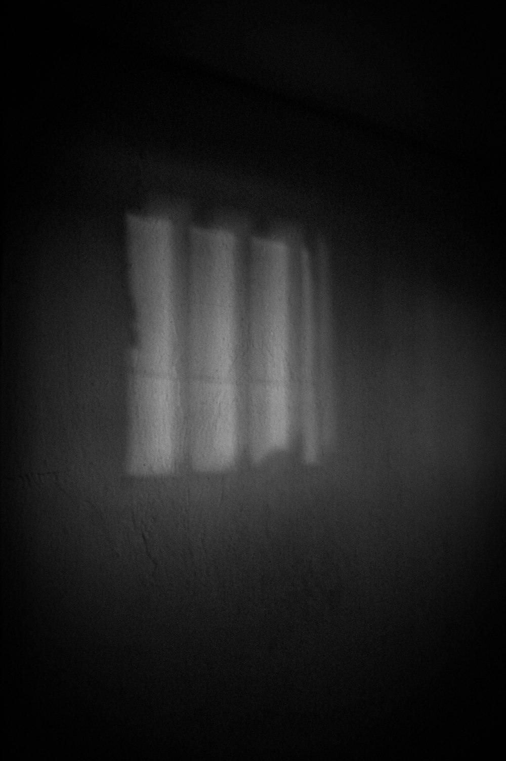 a black and white photo of a window in a dark room