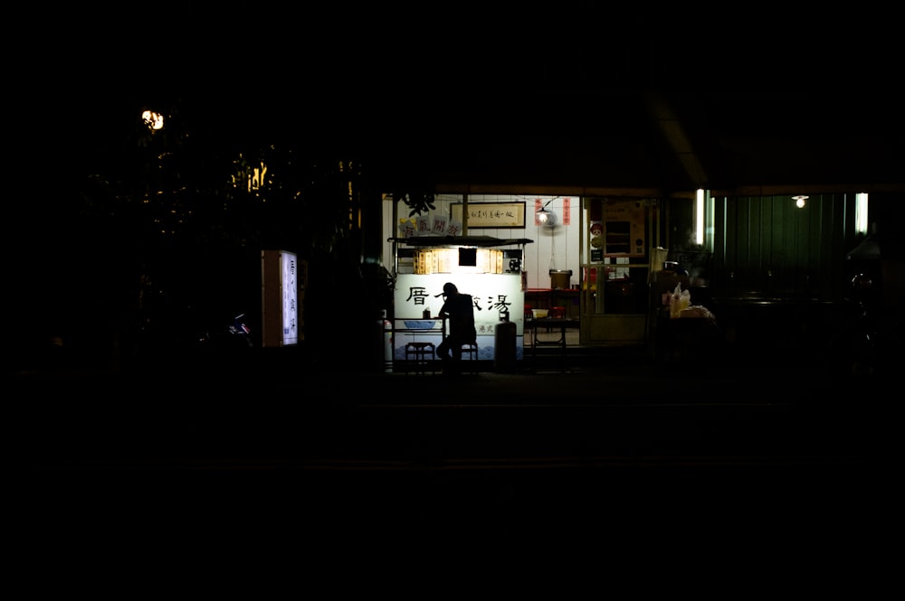 a couple of people standing outside of a building at night