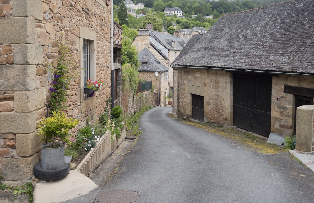 a narrow street with a stone building and a potted planter