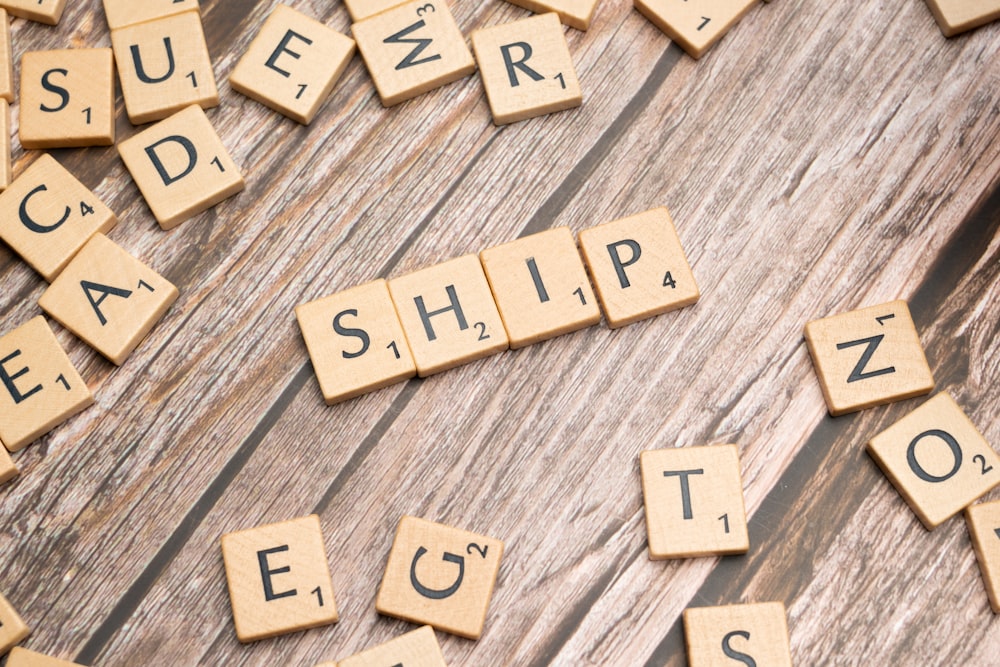 scrabble tiles spelling out the word ship on a wooden surface