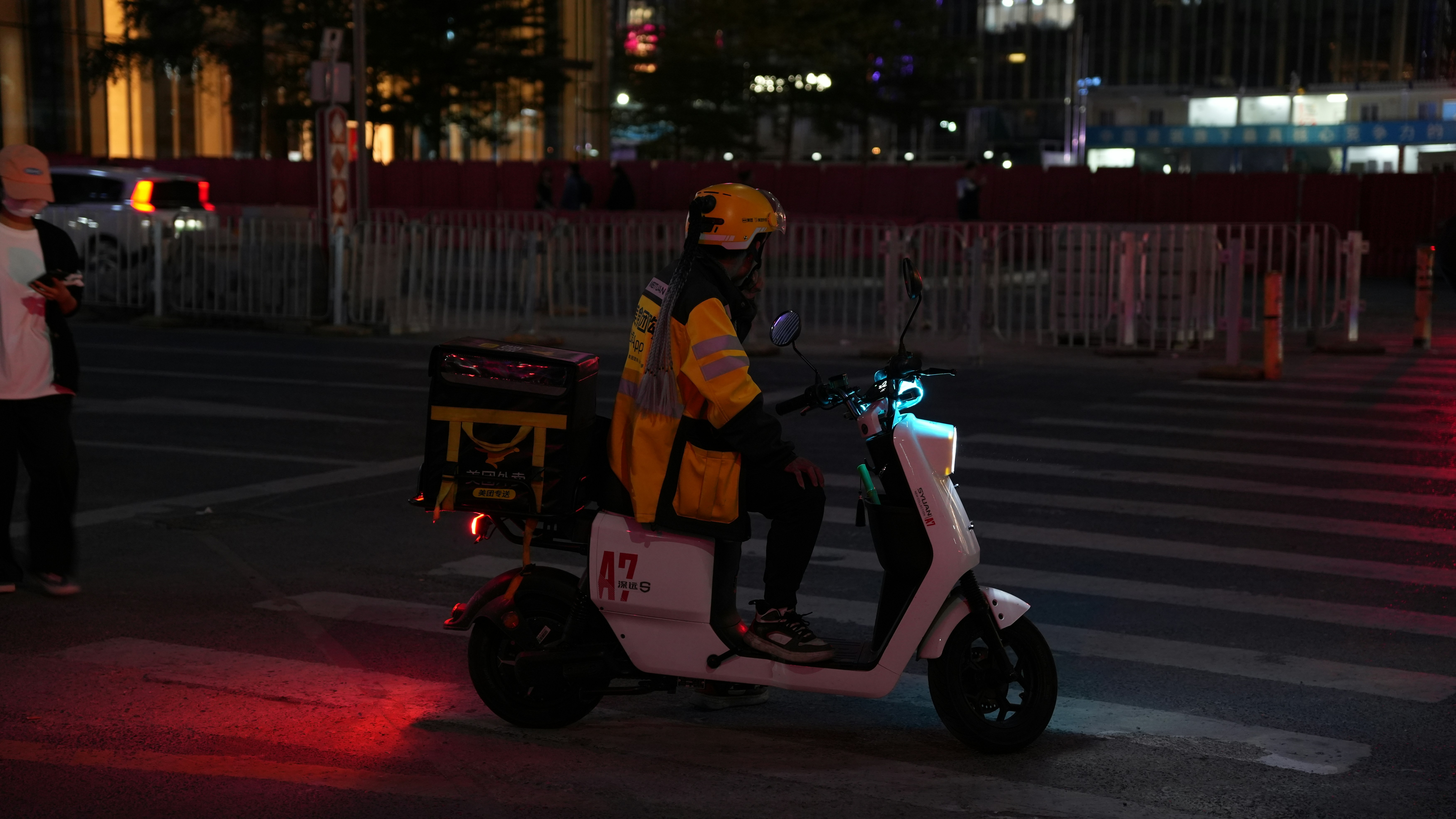 a man riding a scooter down a street at night