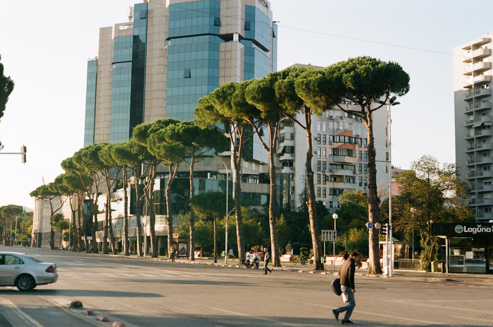 a man walking across a street next to tall buildings