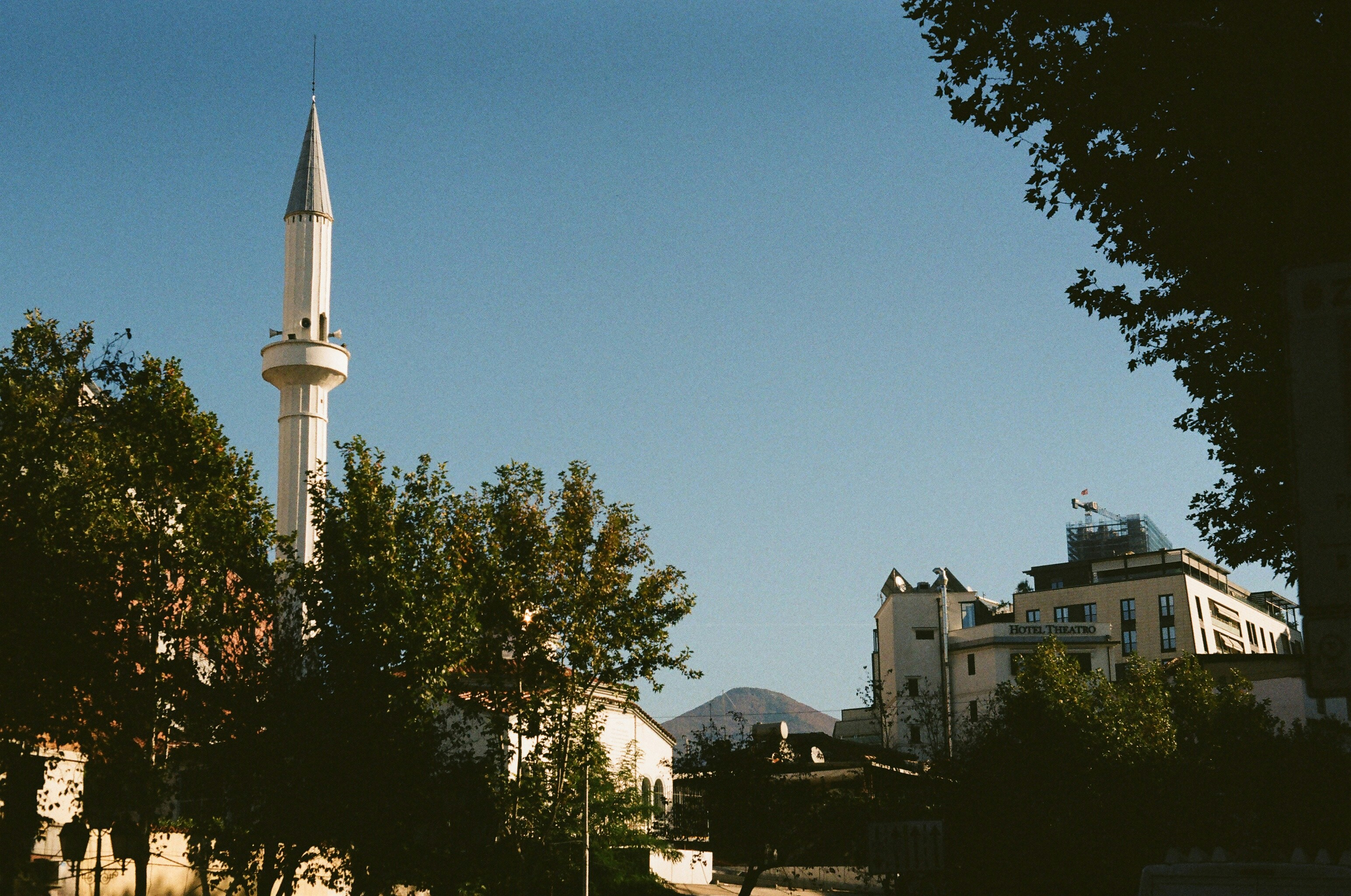 A minaret from a local mosque stands tall above the trees.