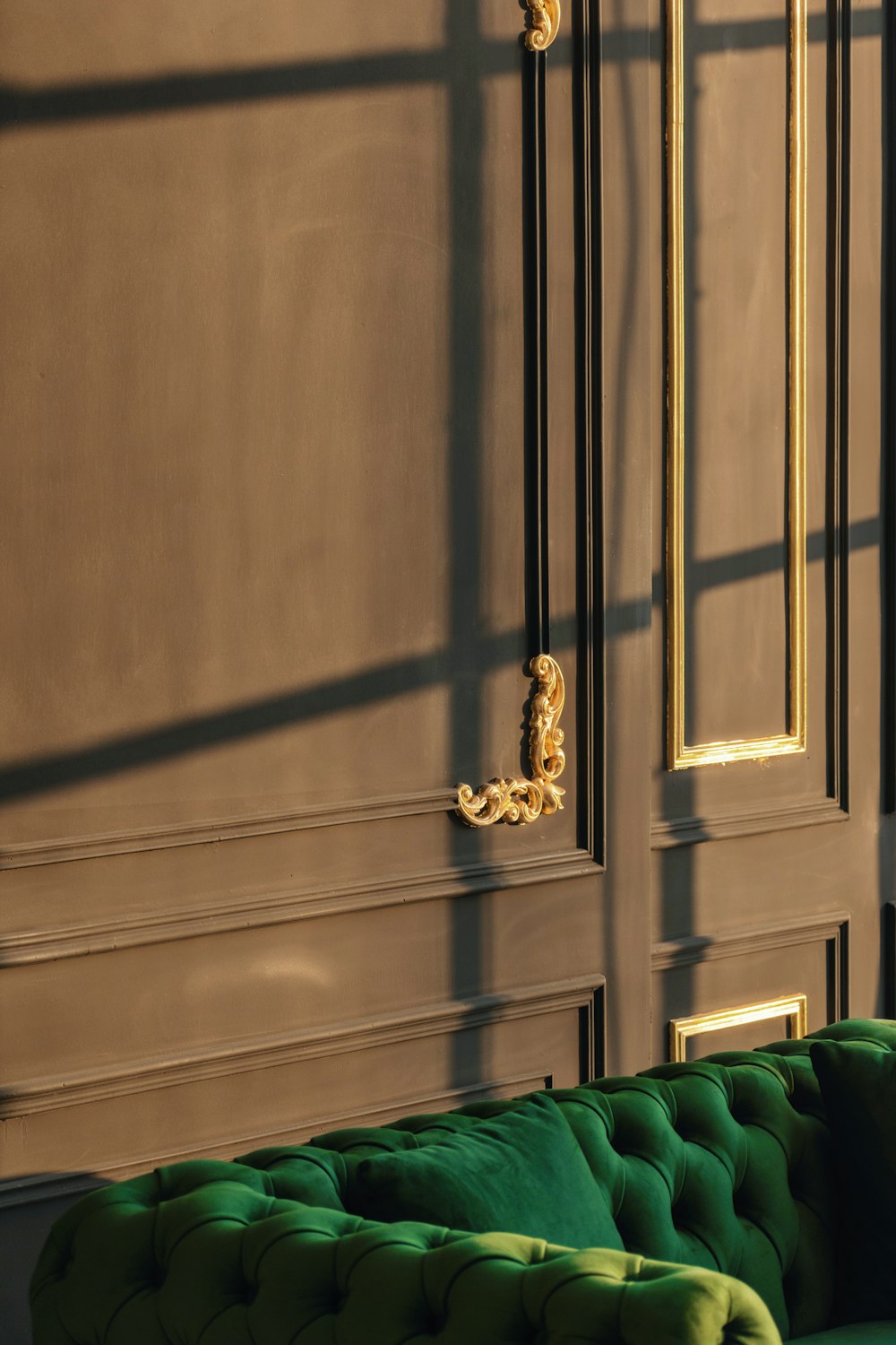 a green couch sitting in front of a brown wall