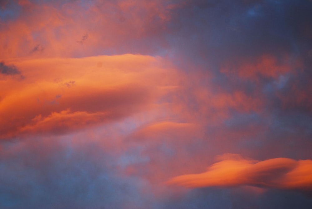 a plane flying through a cloudy sky at sunset