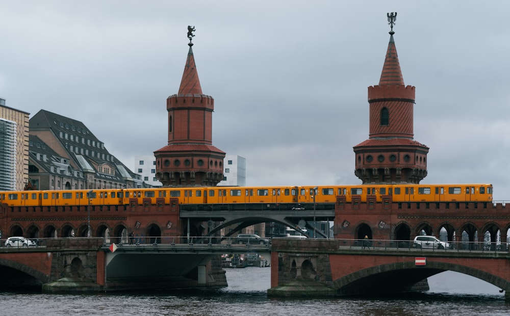 a yellow train is crossing a bridge over water