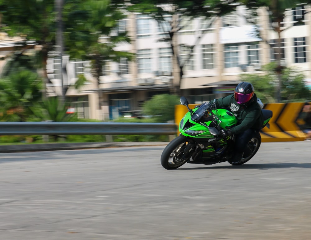 a man riding a green motorcycle down a street