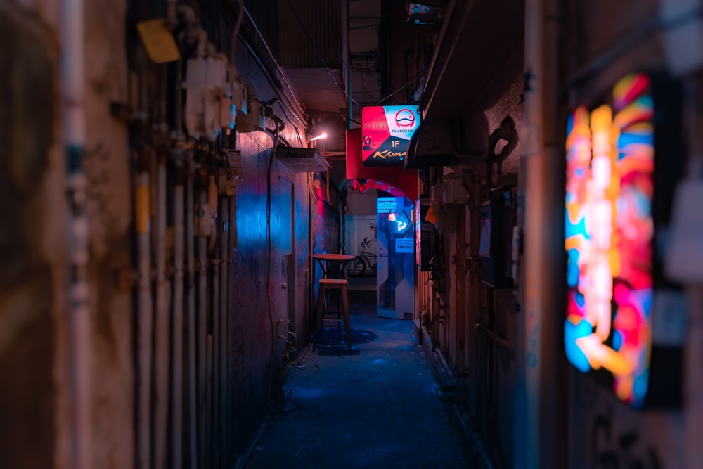 a narrow hallway with a neon sign on the wall