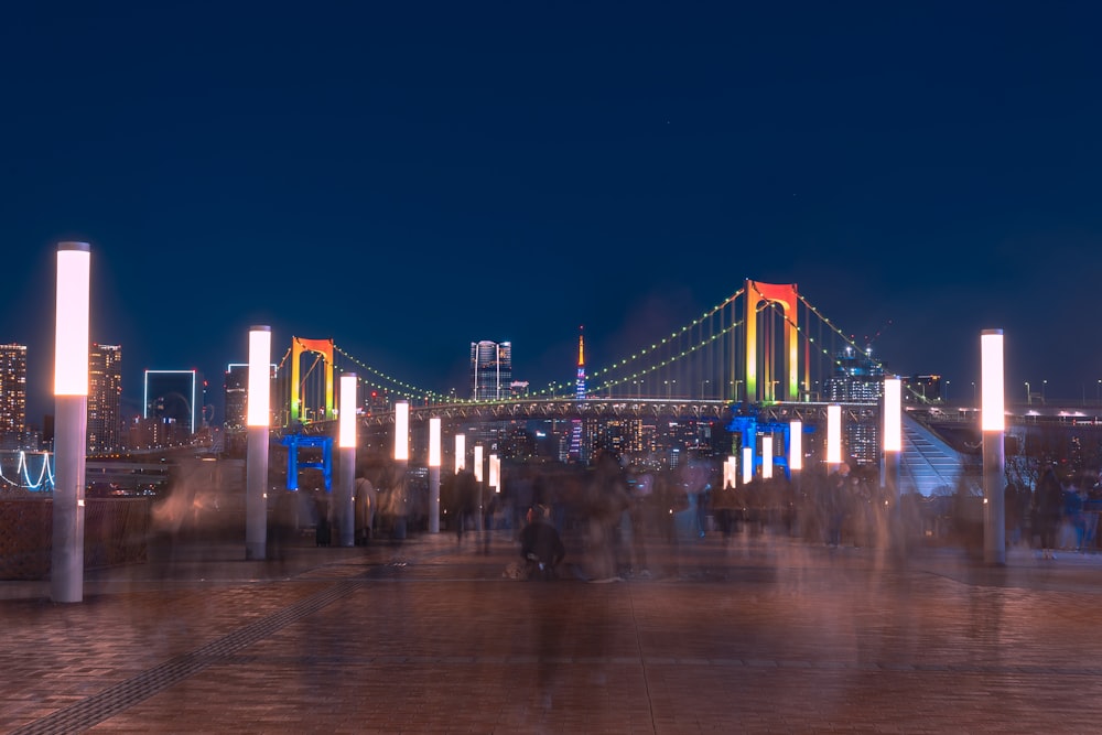 a group of people walking across a bridge at night